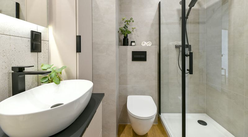 Helles Badezimmer mit schwarzen Akzenten und einer Dusche