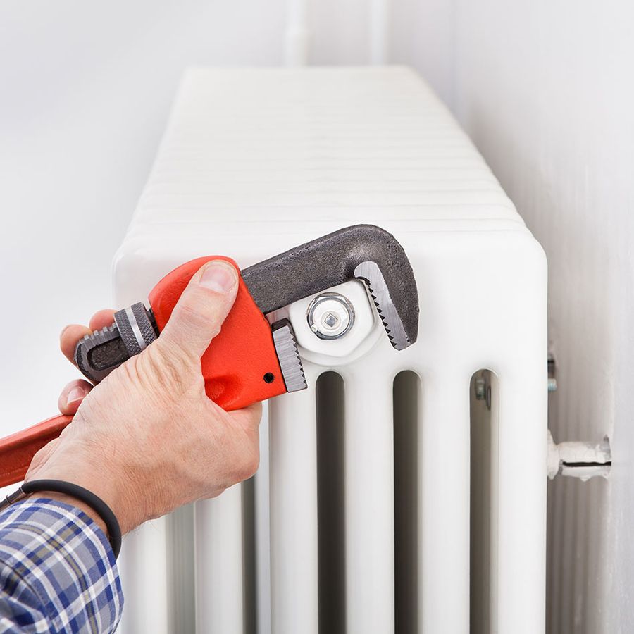 Es wird an einer Heizung mit einer Roten Zange geschraubt